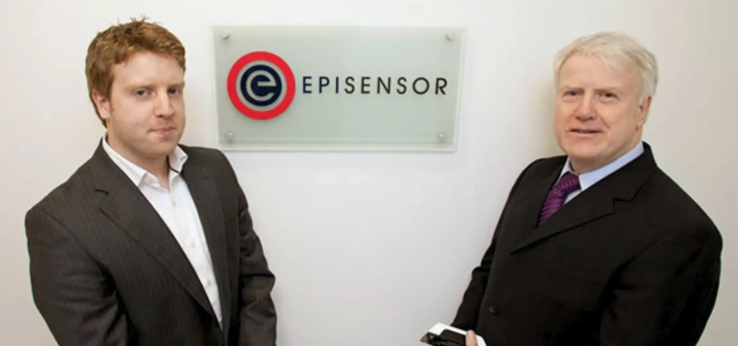 Two men standing either side of the EpiSensor sign at the company office.