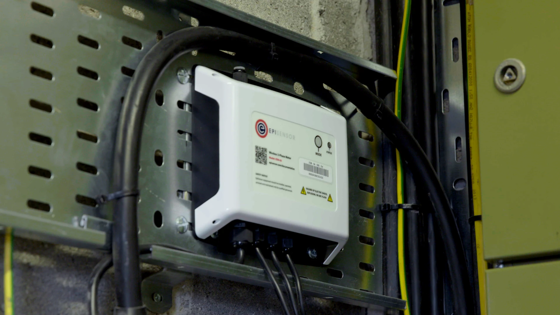 A ZEM electricity monitor fixed to cable tray, with its current sensor leads running down to the supply cables.